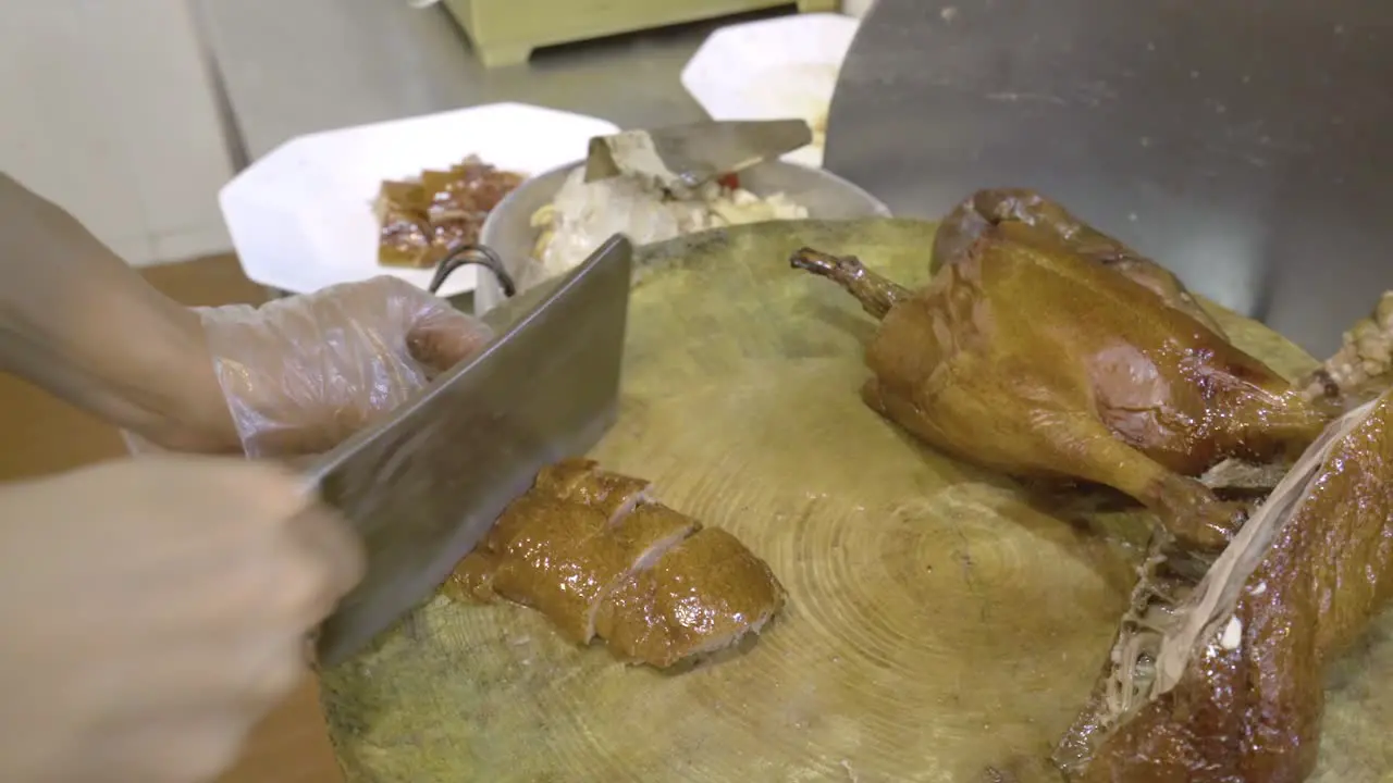 Man's Hands Chopping Roasted Goose With A Butcher's Knife In Guangzhou China close up