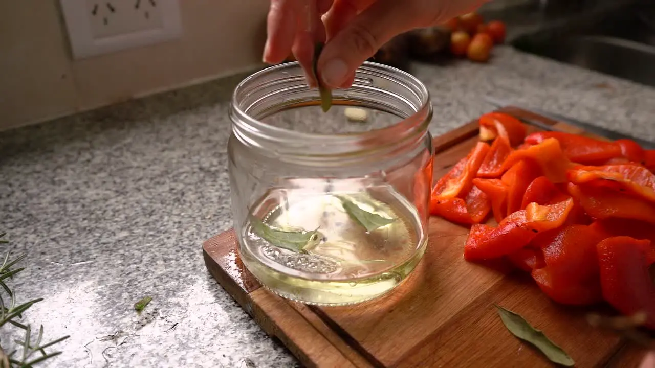 Adding Bay Leaves Into Jar With Sunflower Oil Water And Black Peppercorns