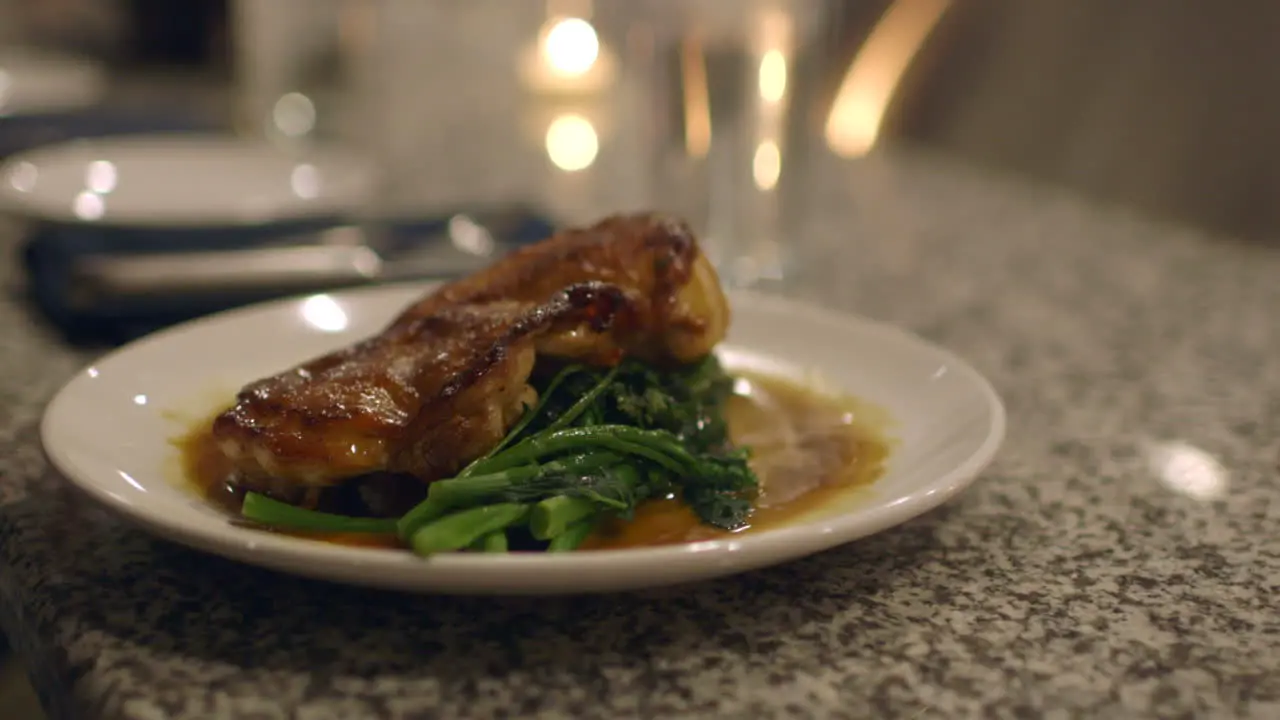 Roast Chicken and Rapini plated on a counter at an upscale restaurant is sliced by customer