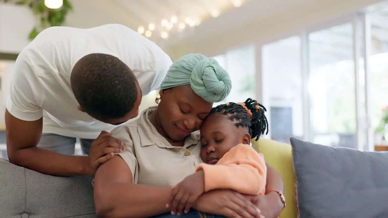 Black family relax and parents hug child on sofa