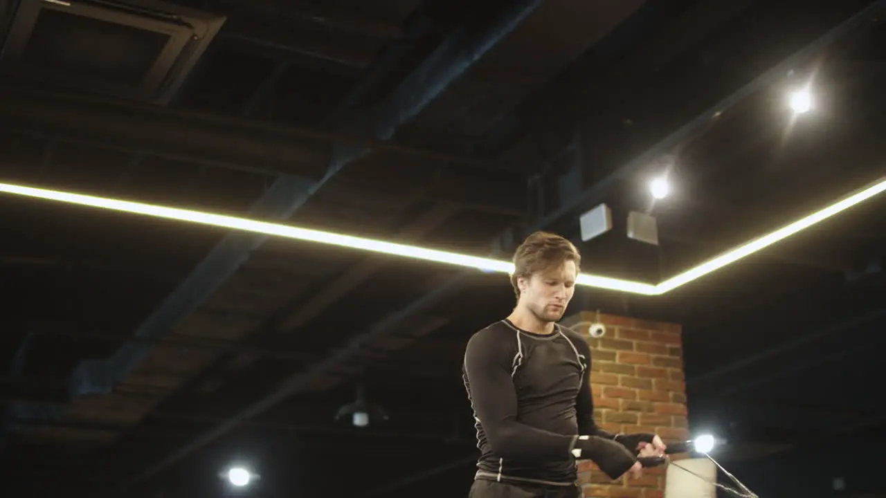 Active boxer using jump rope on boxing ring Sport man doing exercises at gym