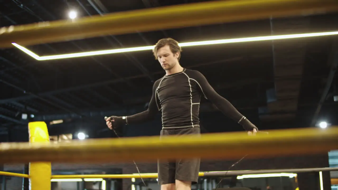 Strict fit man using skipping rope in sport club Sport man warming up at gym