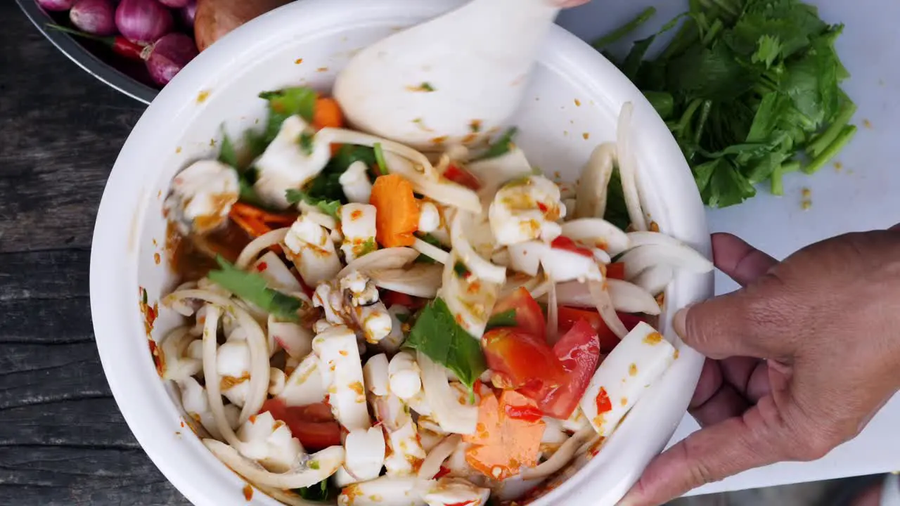 Mixing squid and vegetable dish with spoon for serving top down shot