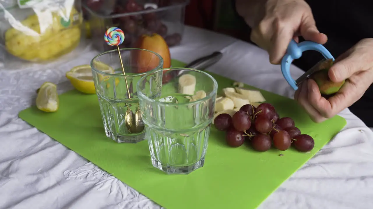 Peeling a kiwi for a fresh fruit breakfast with grapes static camera