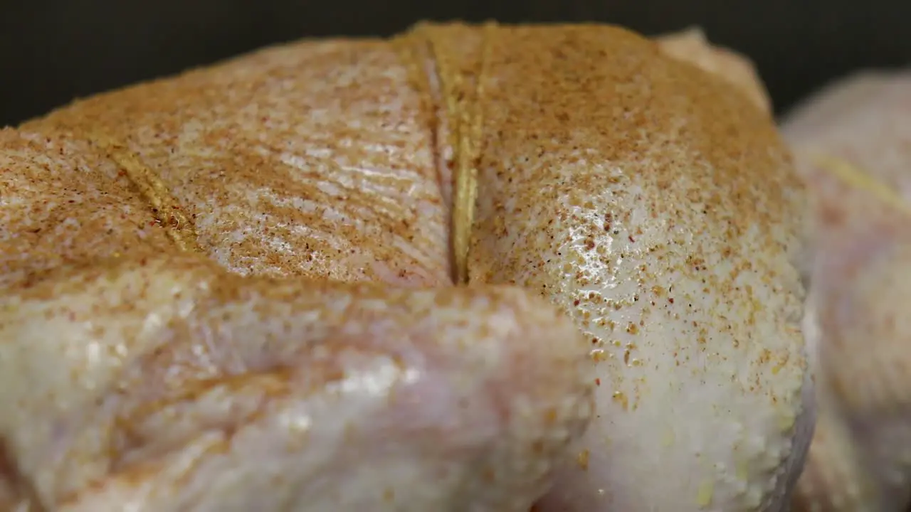 Close up pan right of raw chicken being spiced tied to skewer