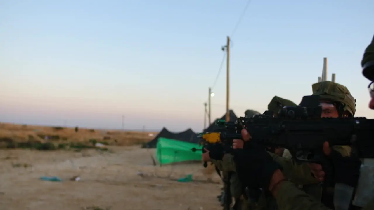 Slow-motion of soldiers lined up and fires an idle bullet while testing their weapons