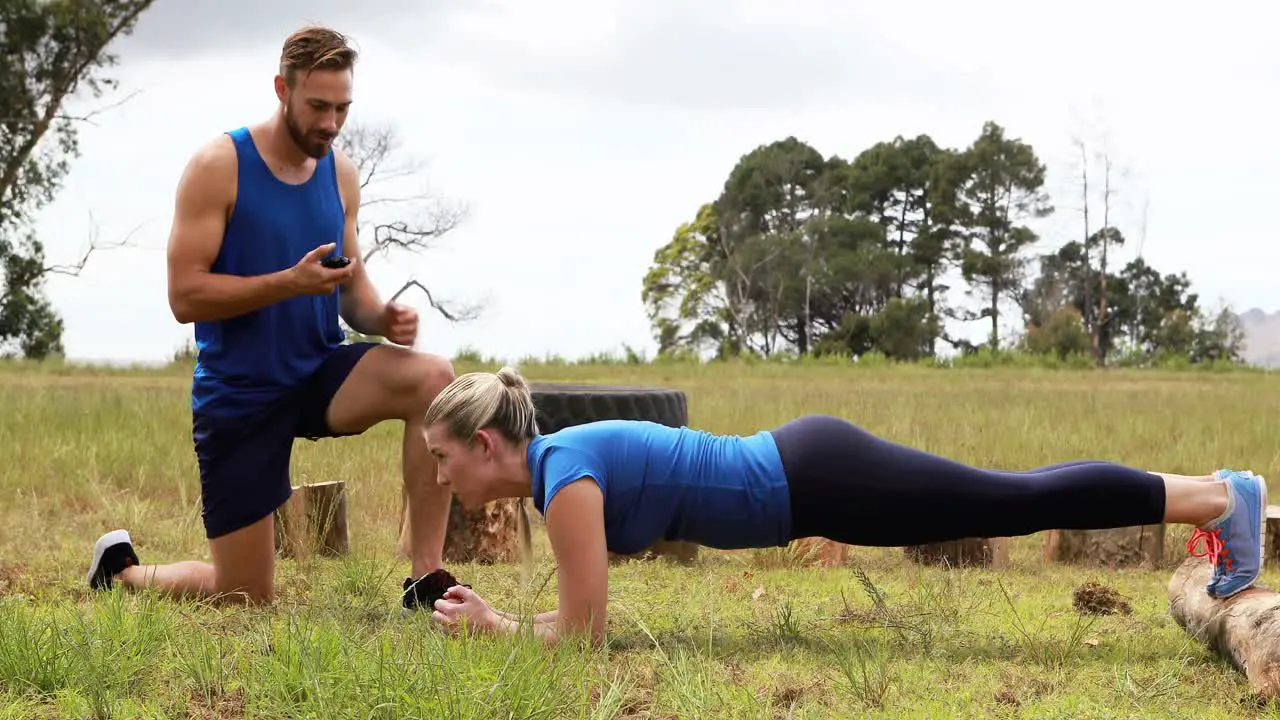 Male trainer training woman during obstacle course