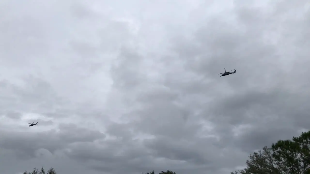 Two helicopters flying in formation across the sky close to the ground while in an attack pattern