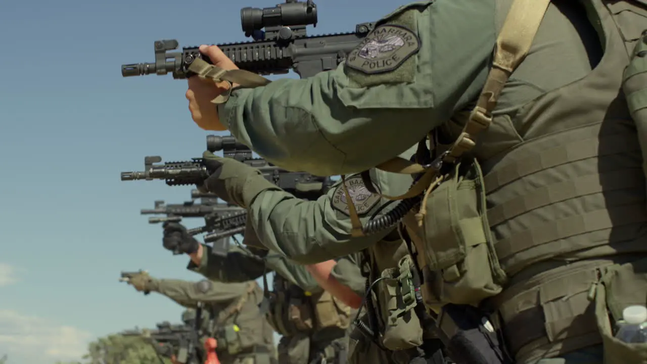 Military personnel in a line as they practice shooting their rifles outdoors