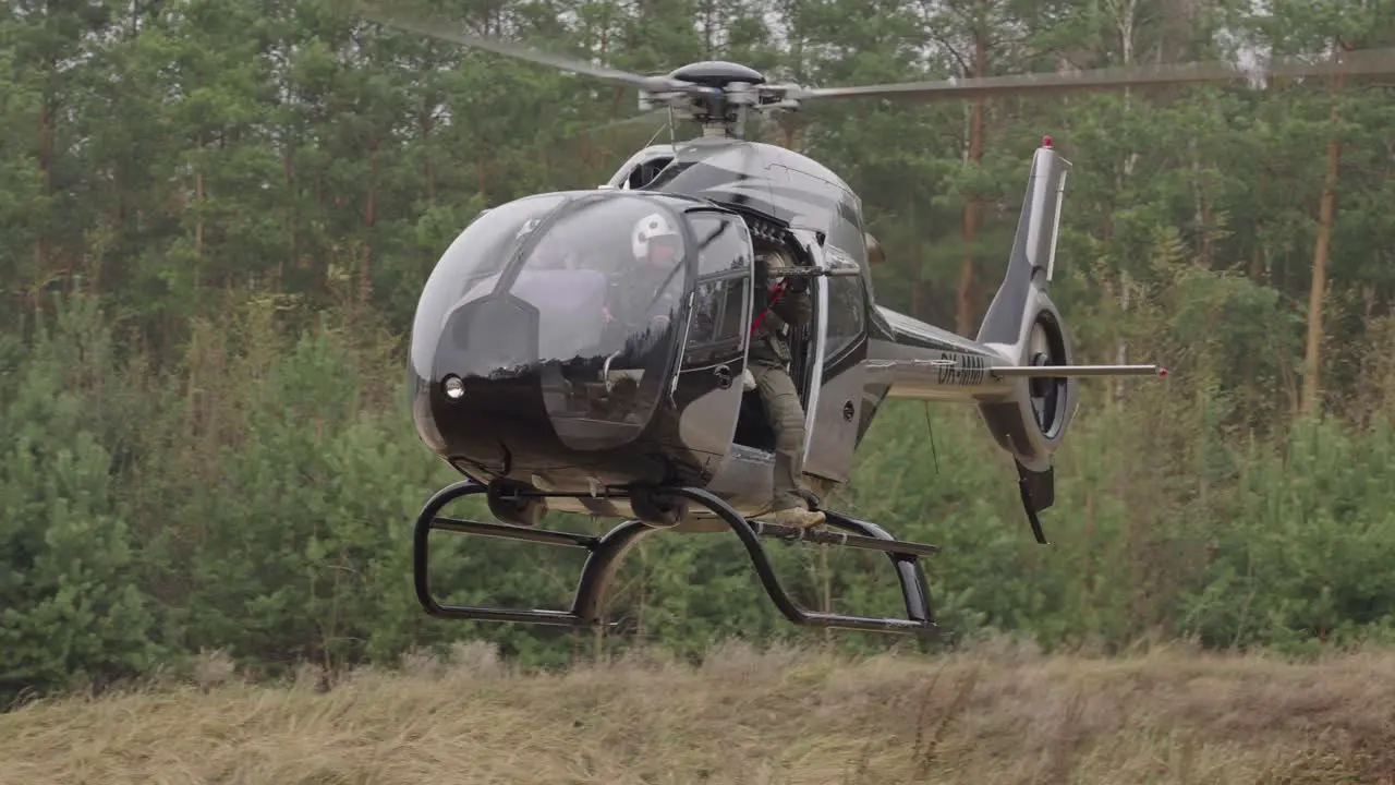 Soldier With Sniper Riffle in Helicopter Flying Above Field Tracking Shot