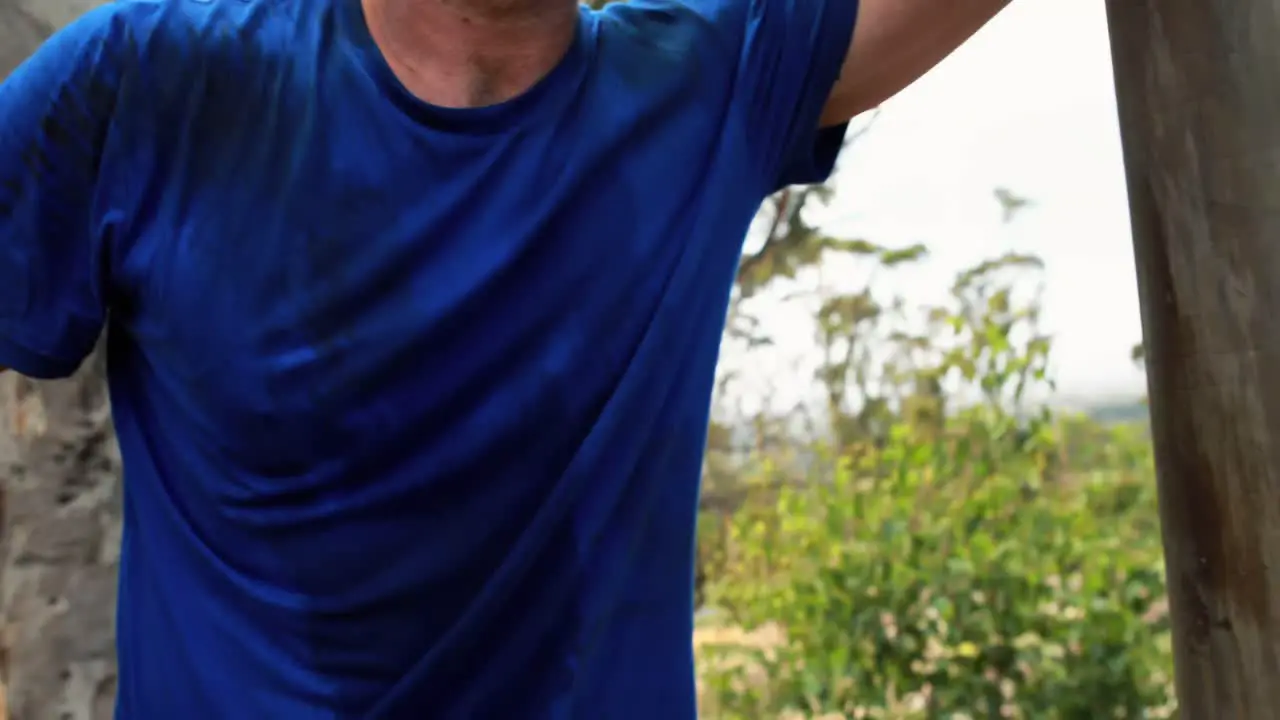 Portrait of fit man leaning on wooden pole during obstacle course