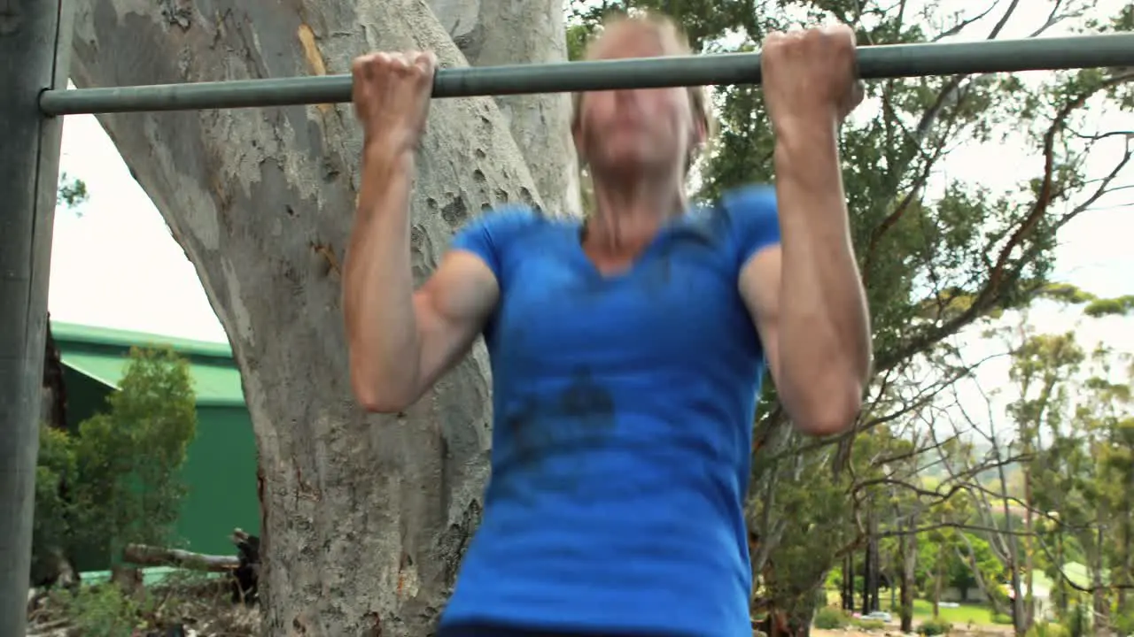 Fit woman exercising on bar during obstacle course