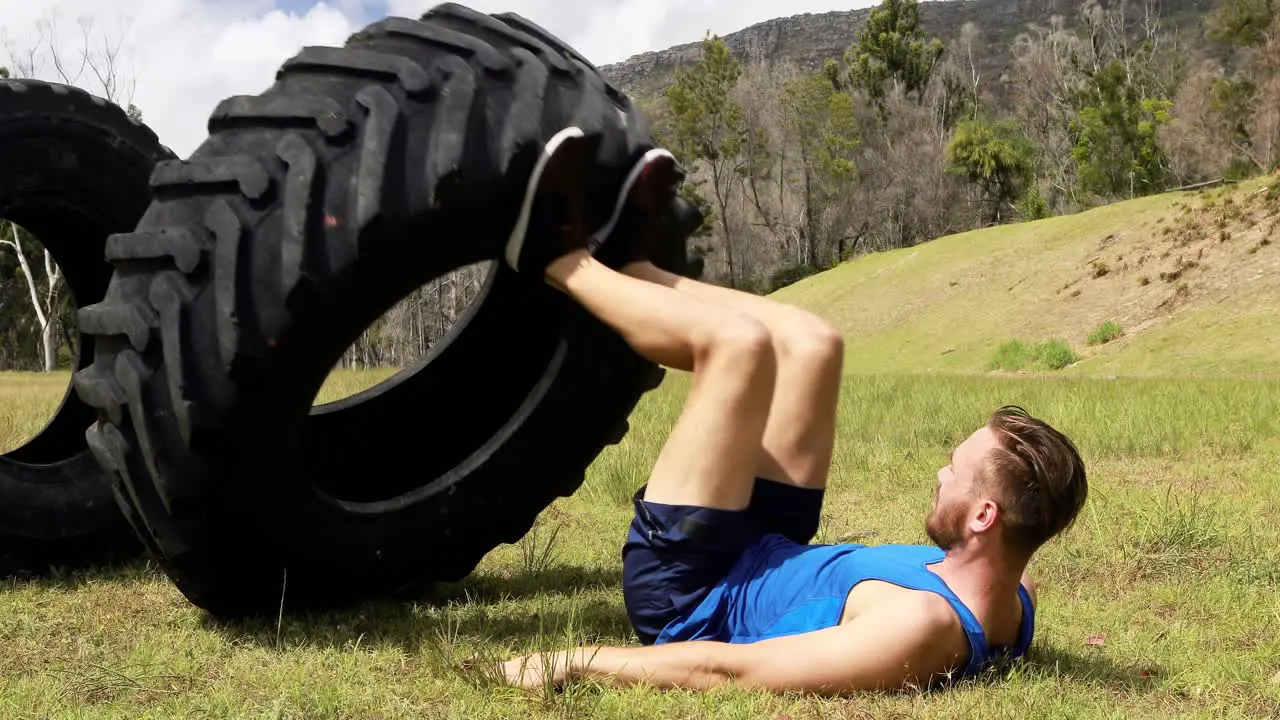 Fit man exercising with heavy tyre during obstacle course