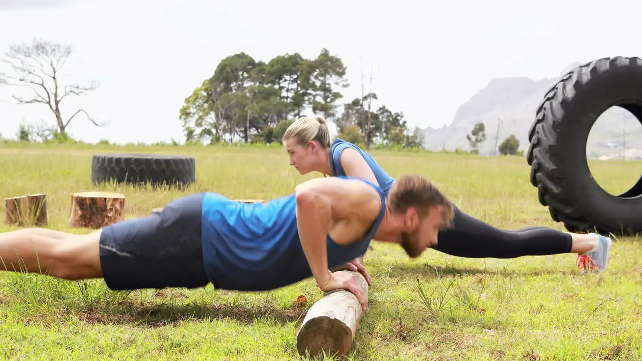 Fit man and woman doing pushup during obstacle course