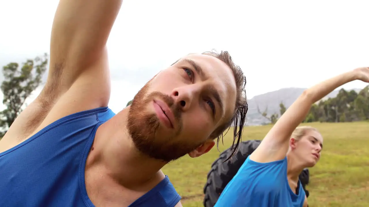 Fit man and woman performing stretching exercising during obstacle course