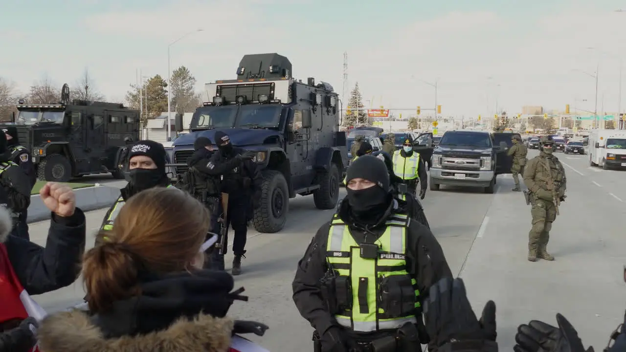 Large military vehicles and armed officers in black block off road in Canada