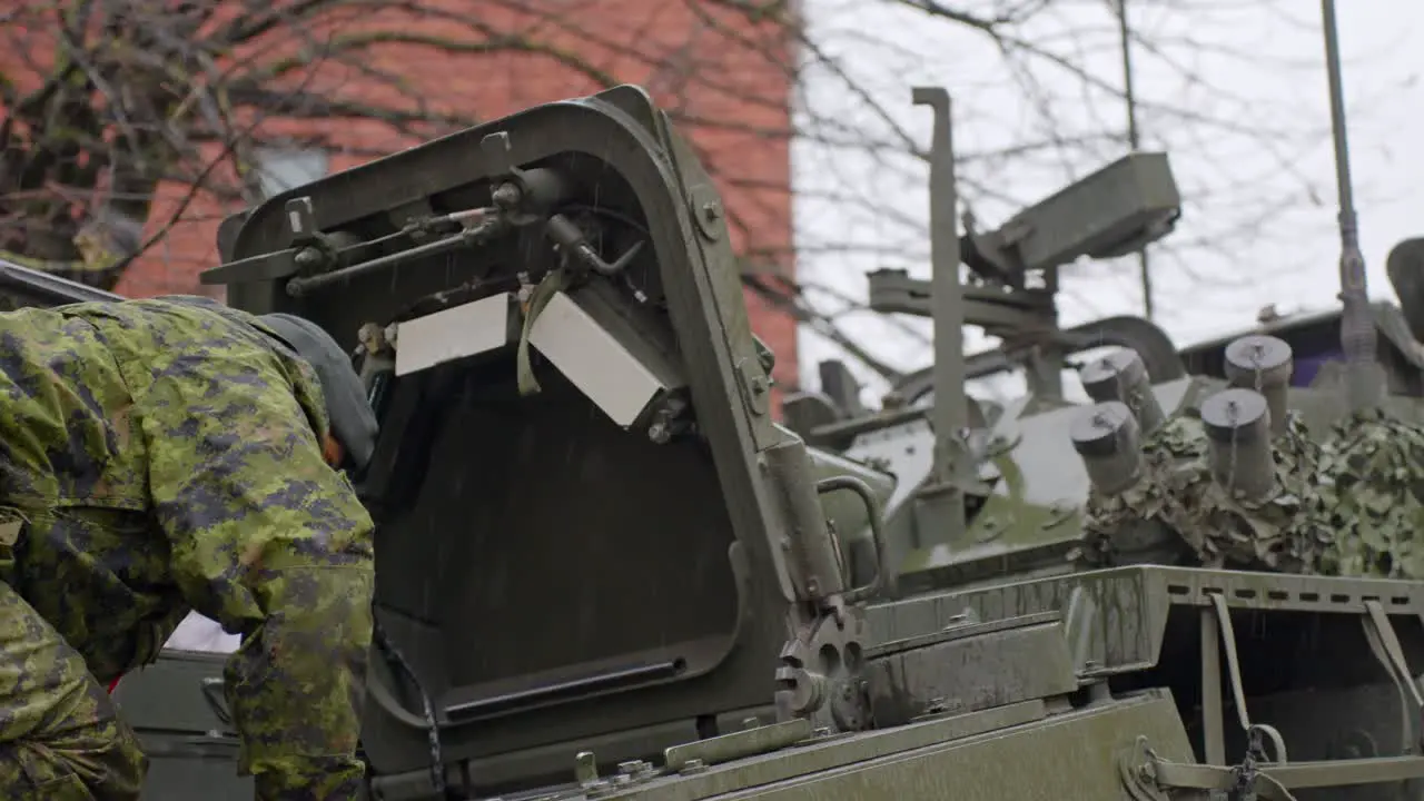 Solider looking inside LAV 6 armored vehicle wearing uniform on a rainy day