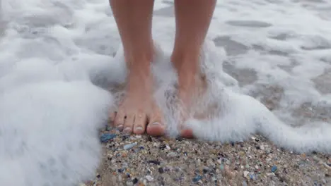 Beach woman feet and standing in water