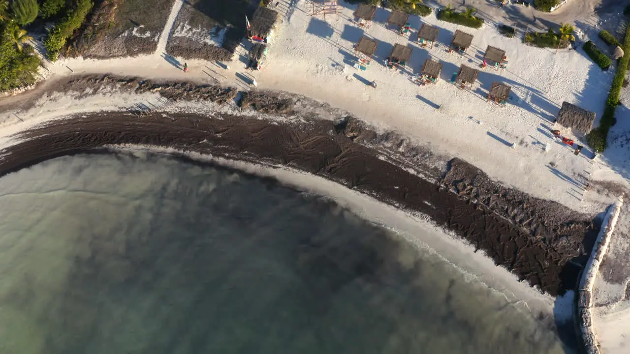 Sandy beach with deck chairs and black sand washed by small waves