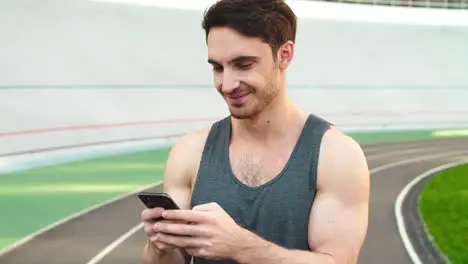 Closeup runner standing with smartphone on track Sporty man holding phone