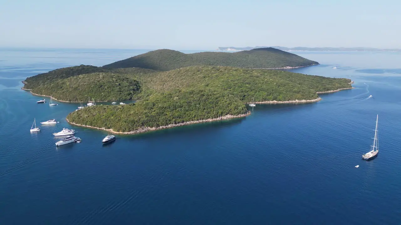 Boats sail near idyllic Green Island in Ionian Sea at Syvota Epirus Greece