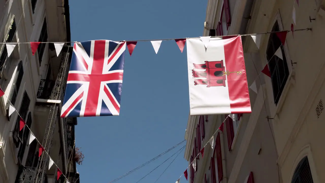 Flags of Great Britain and Gibraltar hanging on rope between houses