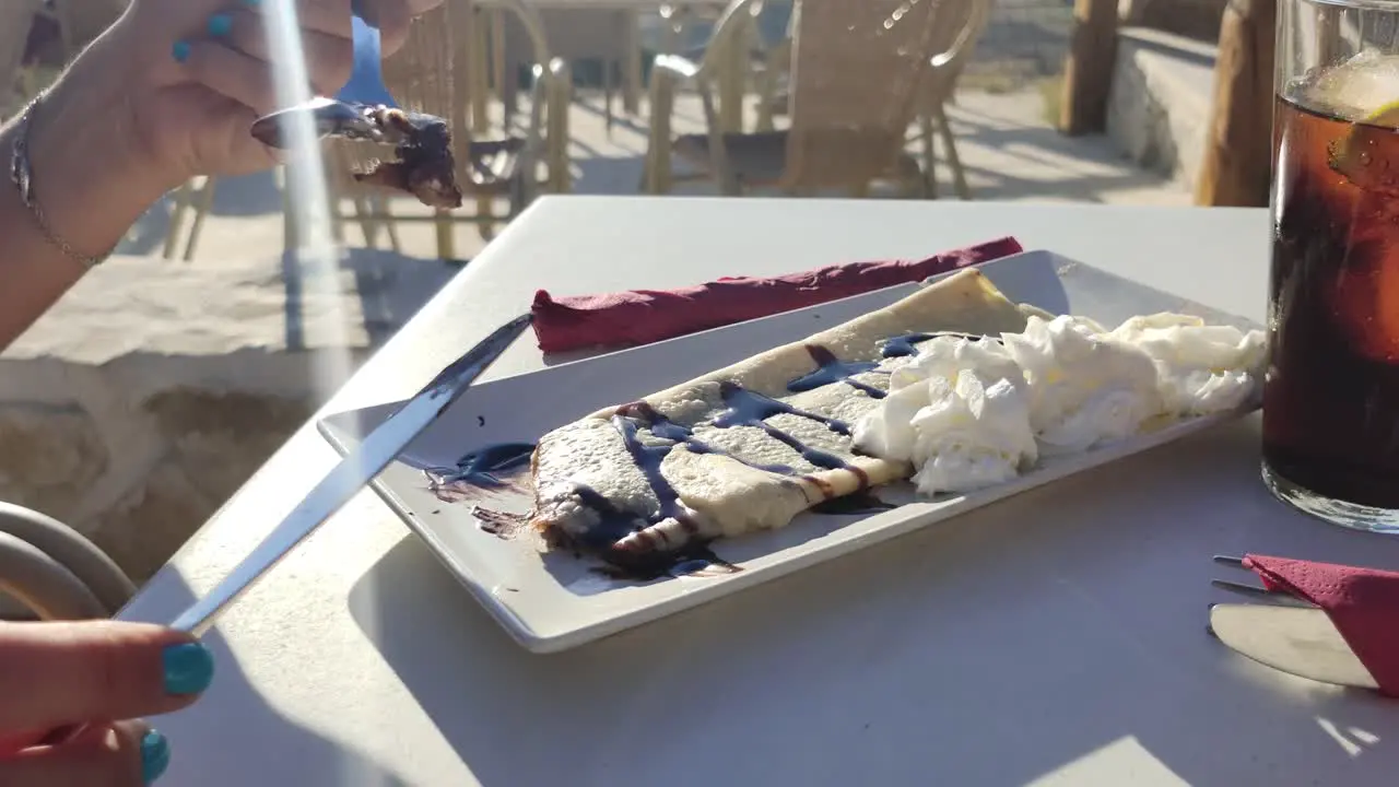 Woman's hands cutting a crepe with syrup in