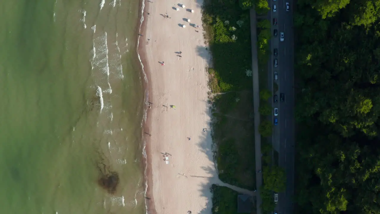 Aerial birds eye overhead top down view of Baltic sea coastline beach with people walking on shore Scharbeutz Germany forward day