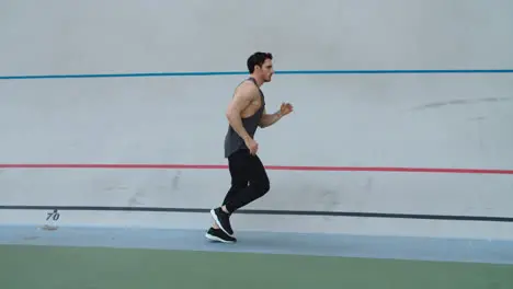 Sport man running in slow motion on track Man runner jogging on athletics track