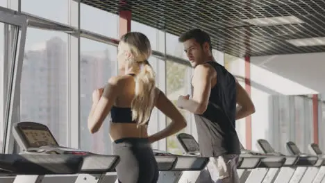 Fitness couple running on treadmill machine in gym club together