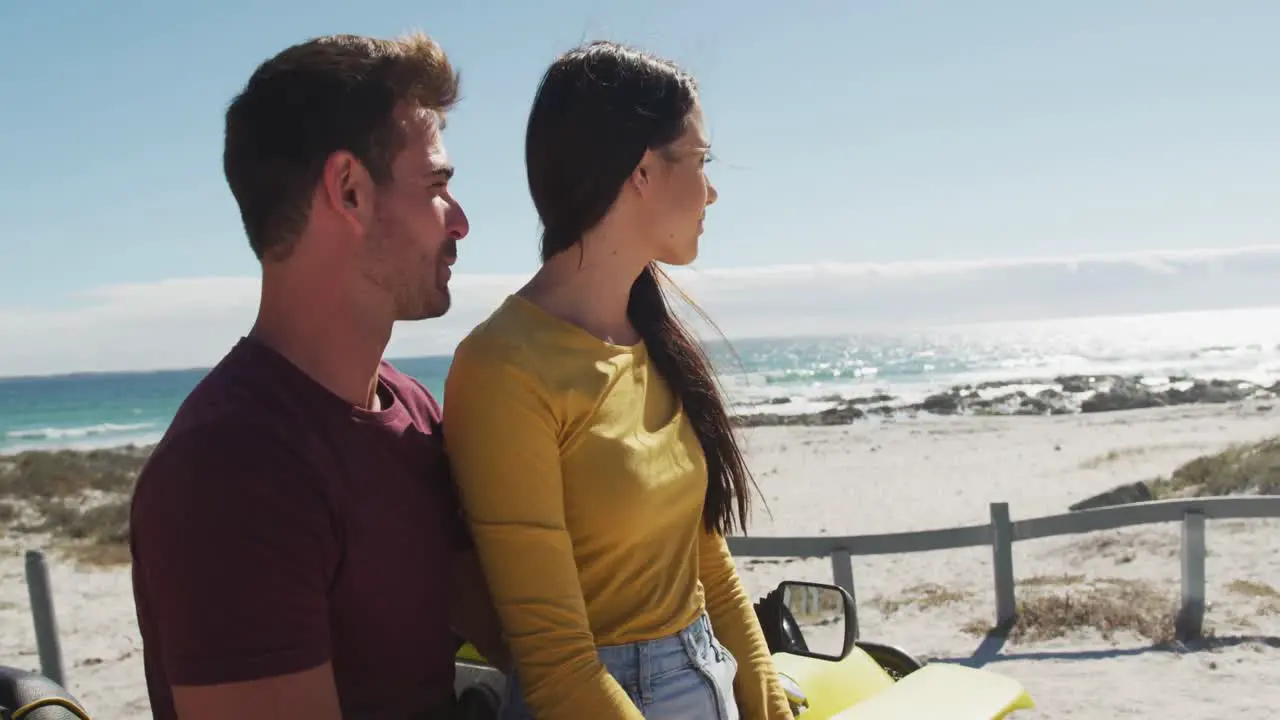 Happy caucasian couple sitting in beach buggy by the sea talking