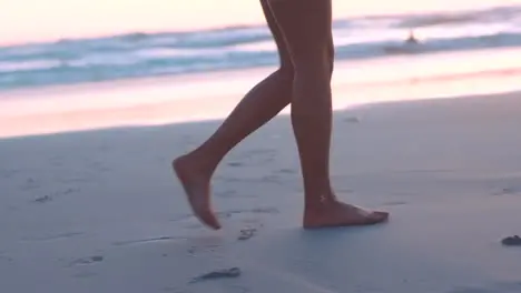 Feet sand and woman walking along a beach