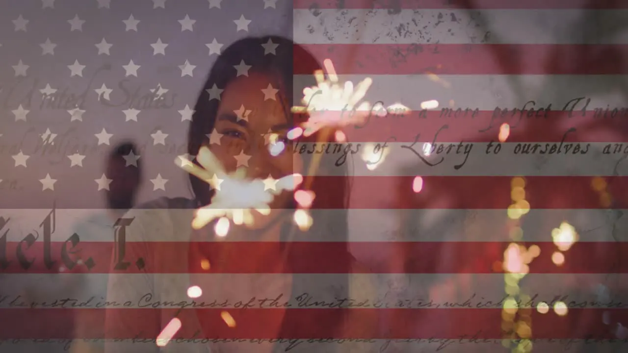 Waving american flag and constitution text against woman enjoying with sparklers at the beach