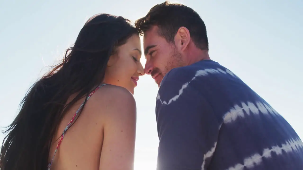 Happy caucasian couple sitting by the sea flirting