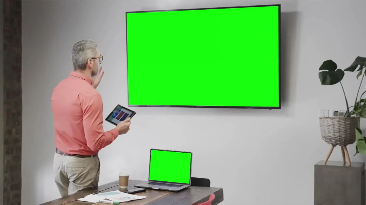 Caucasian businessman on video call with green screen tv screen