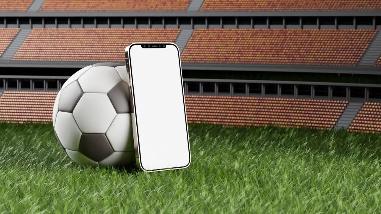 Cellphone with white screen leans agains soccer ball on green field