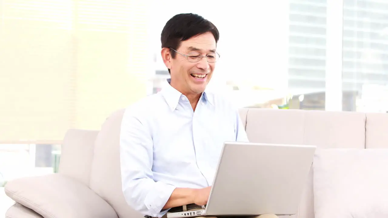 Asian man using laptop on the sofa