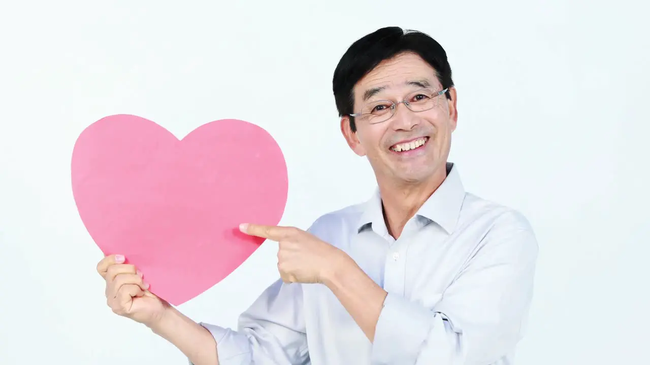 Smiling Asian man holding a pink heart