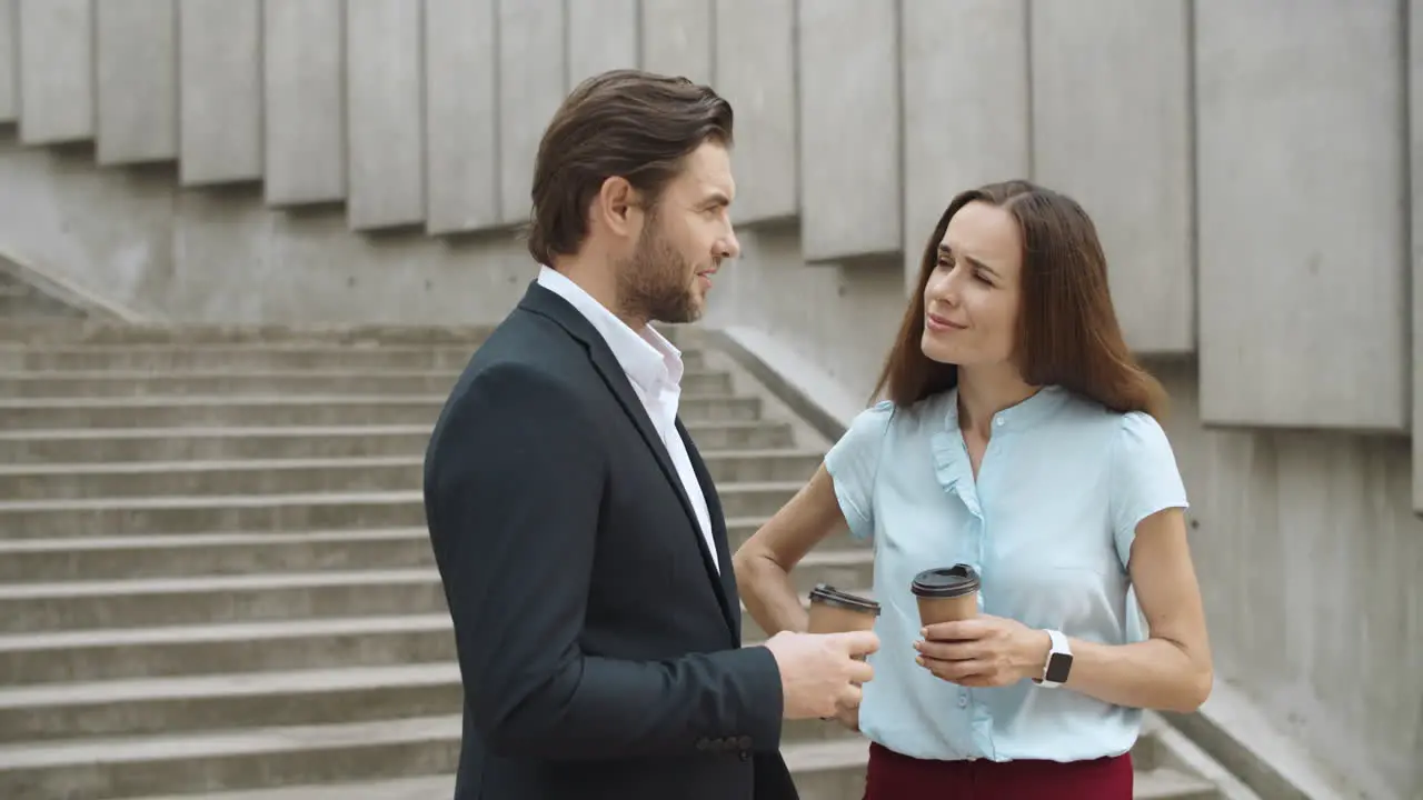 Managers with coffee to go talking on street Friends laughing outdoors