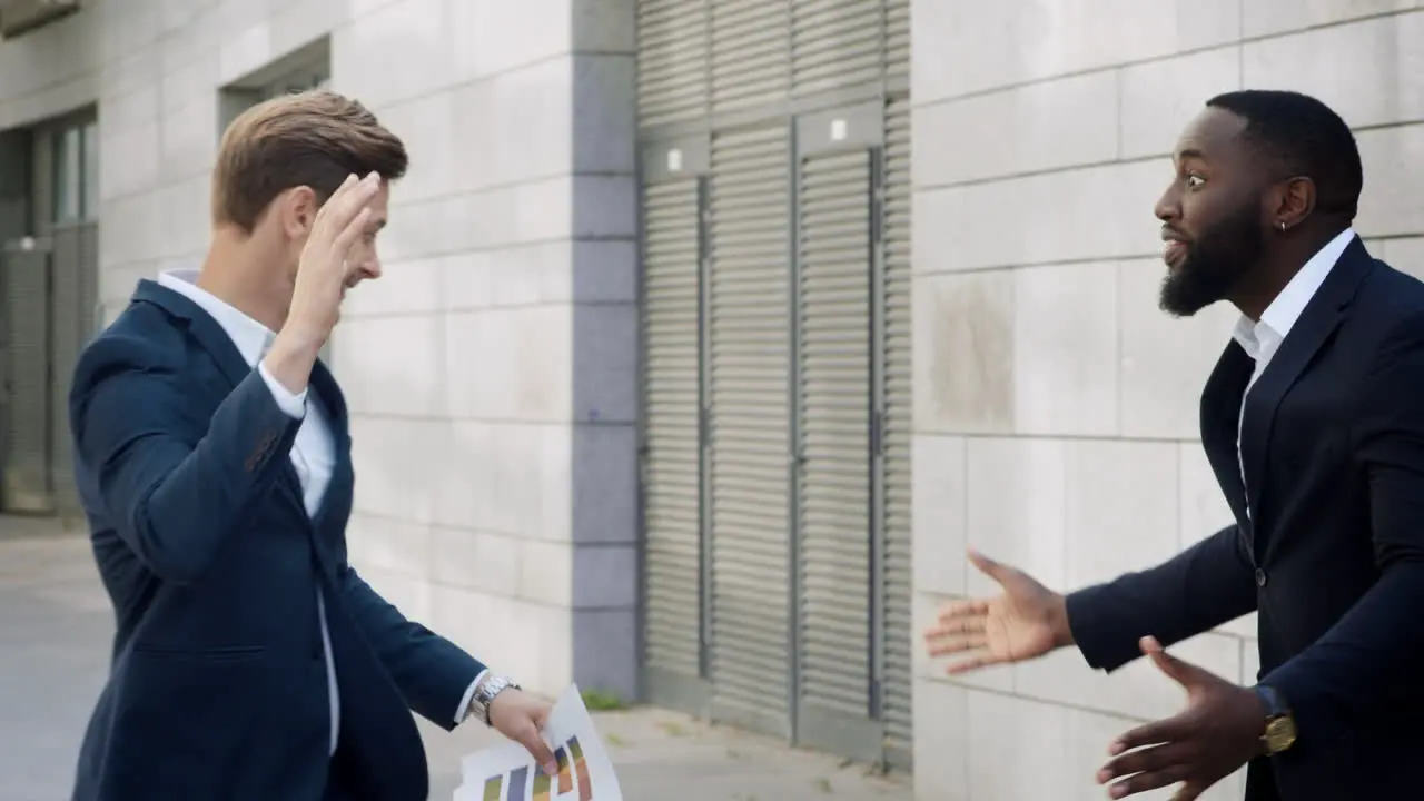 Businessmen reading good news on papers Business partners hugging outdoors