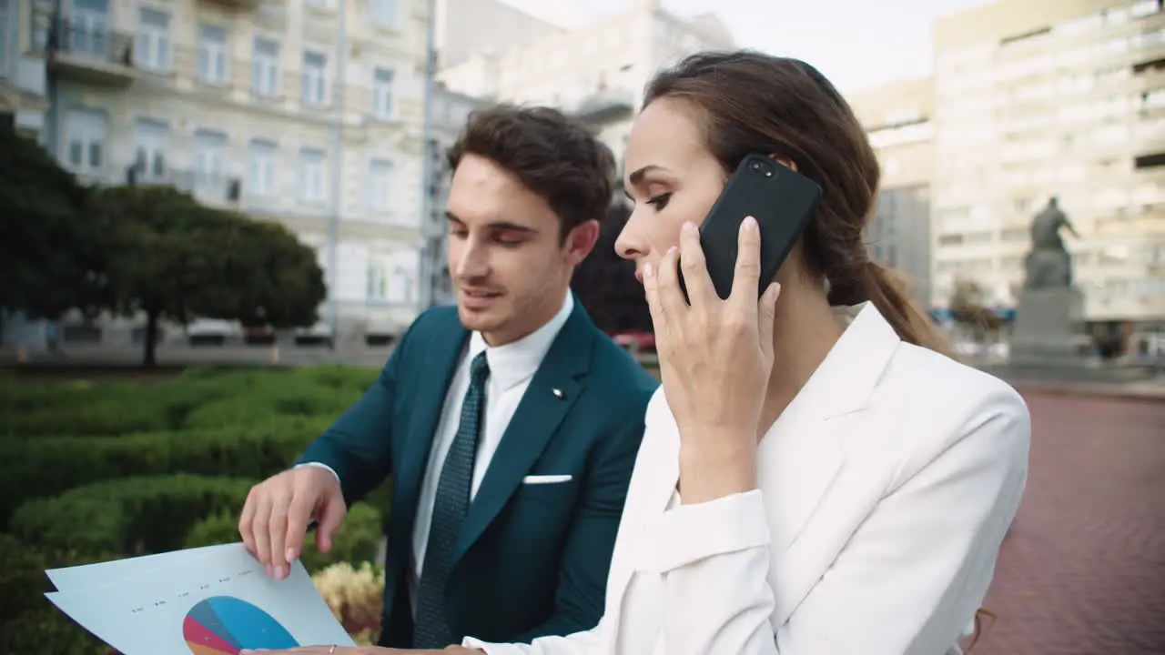 Handsome business man showing data in documents to beautiful woman in street