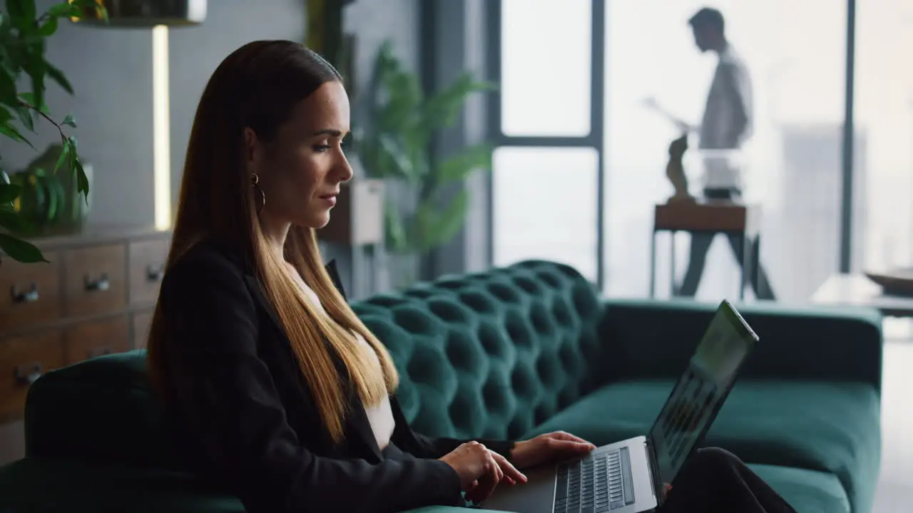 Businesswoman using laptop computer in office Businessman walking indoors