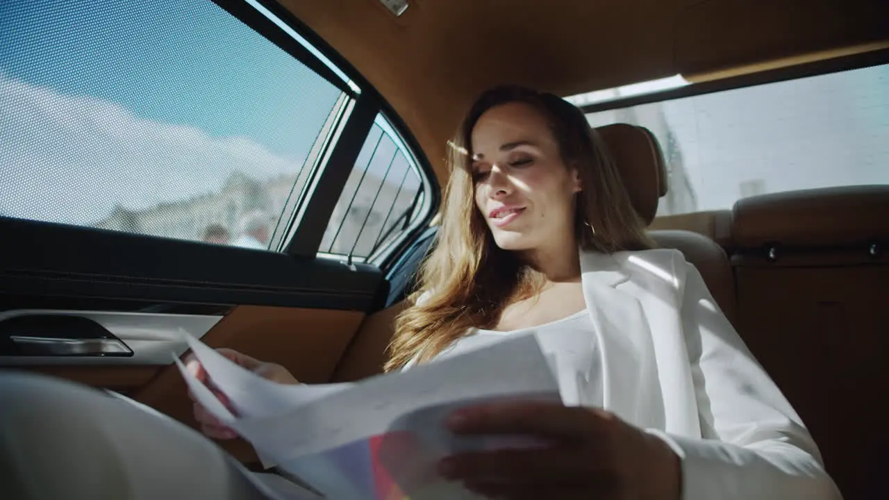 Cheerful business woman analysing statistics in documents in automobile