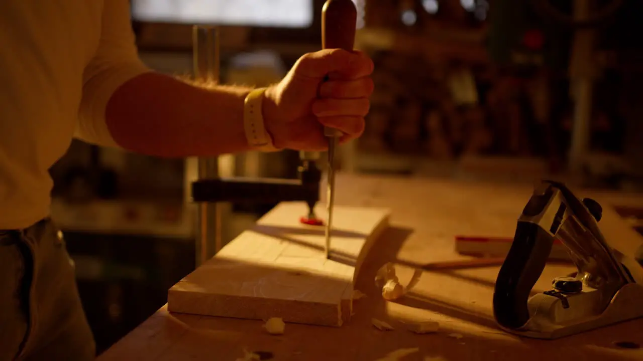 Close up of craftsman making a hole in wood with a hammer in workshop