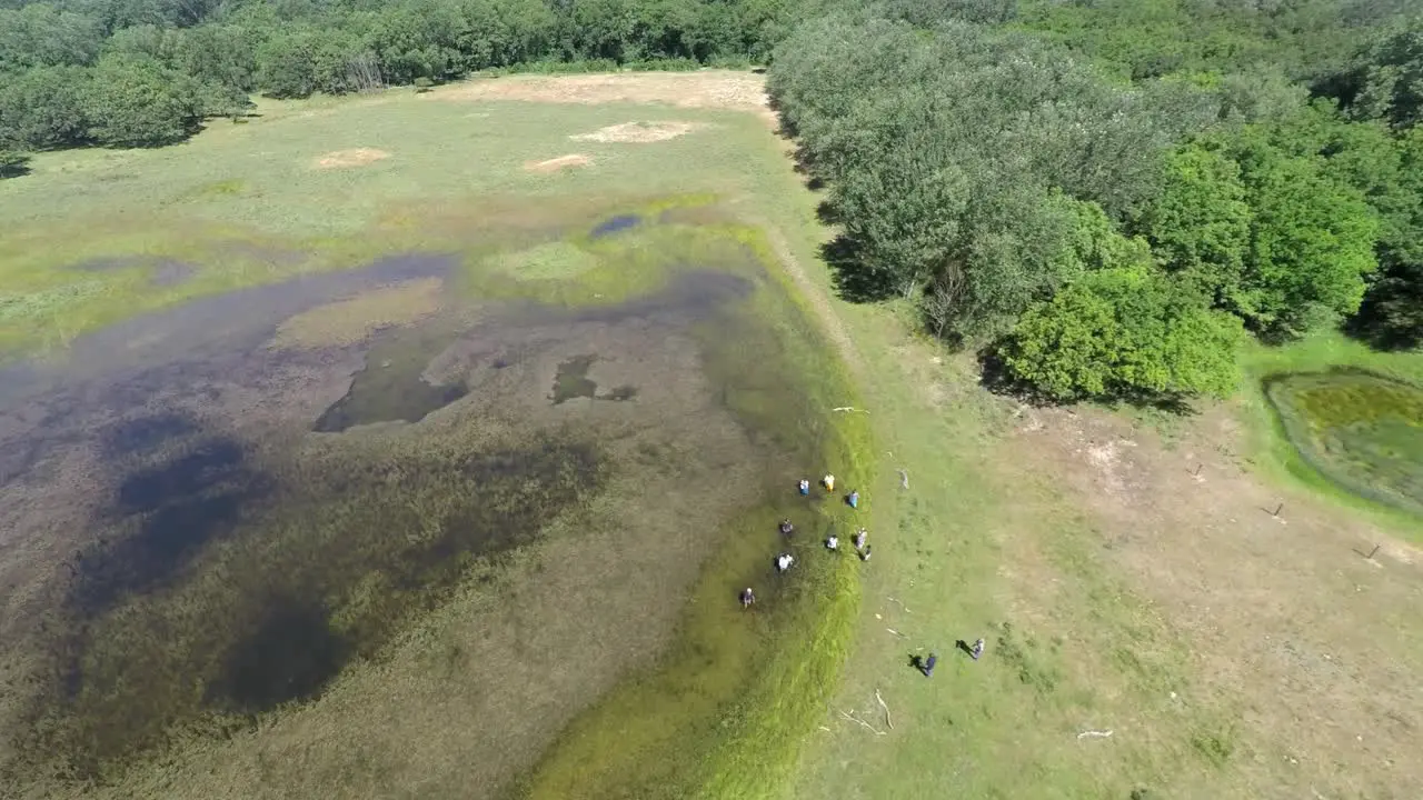 Aerial footage of forest pond and a small group of refugees