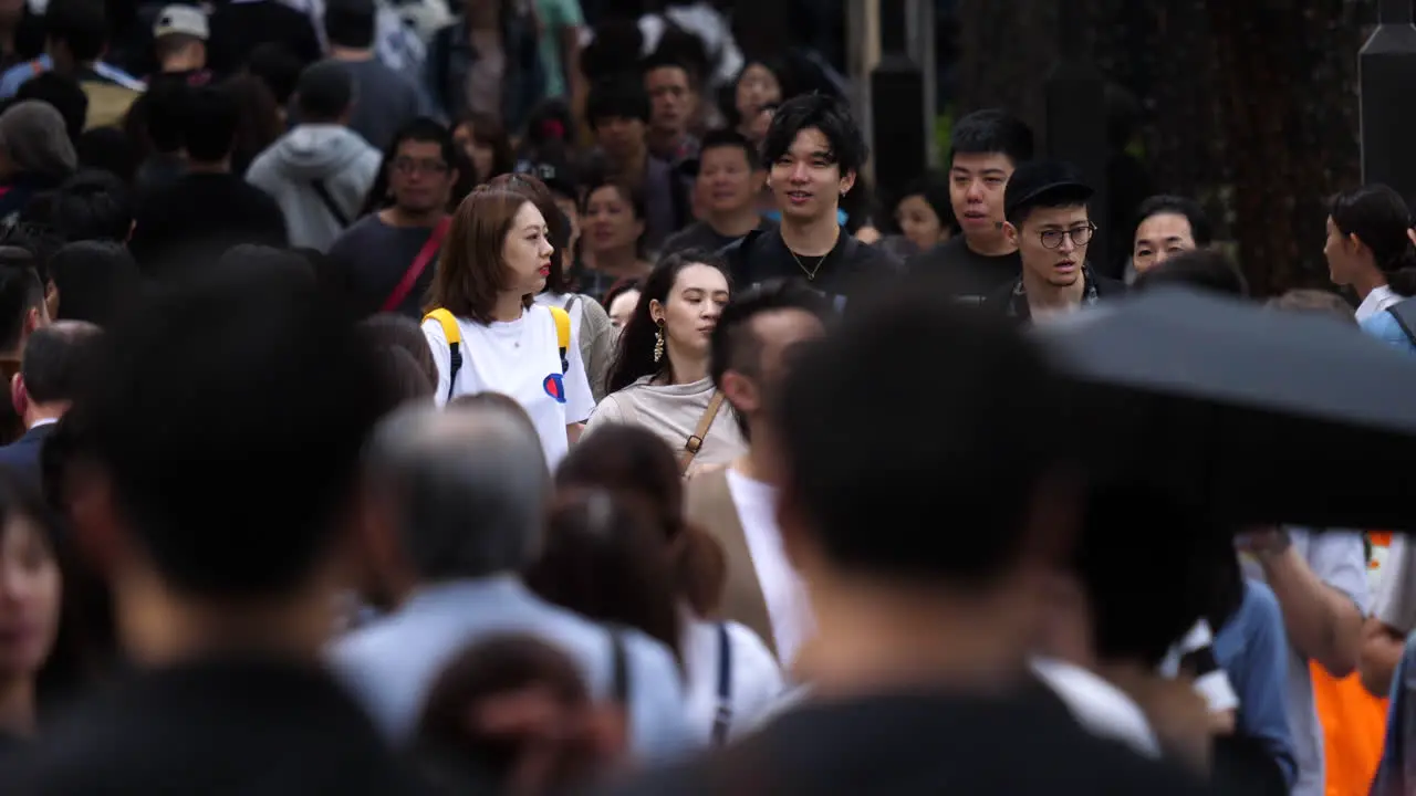 Static shot of a woman walking in middle of a large crowd on the streets of Harajuku in Tokyo Japan