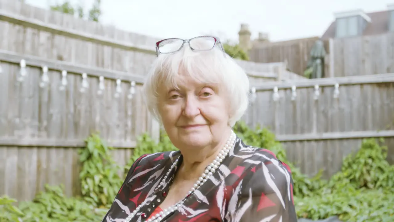 Elderly Woman smiling at camera tilting her head in her garden day