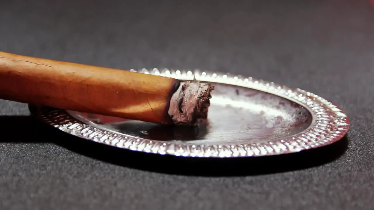 lit cigar resting on silver ashtray