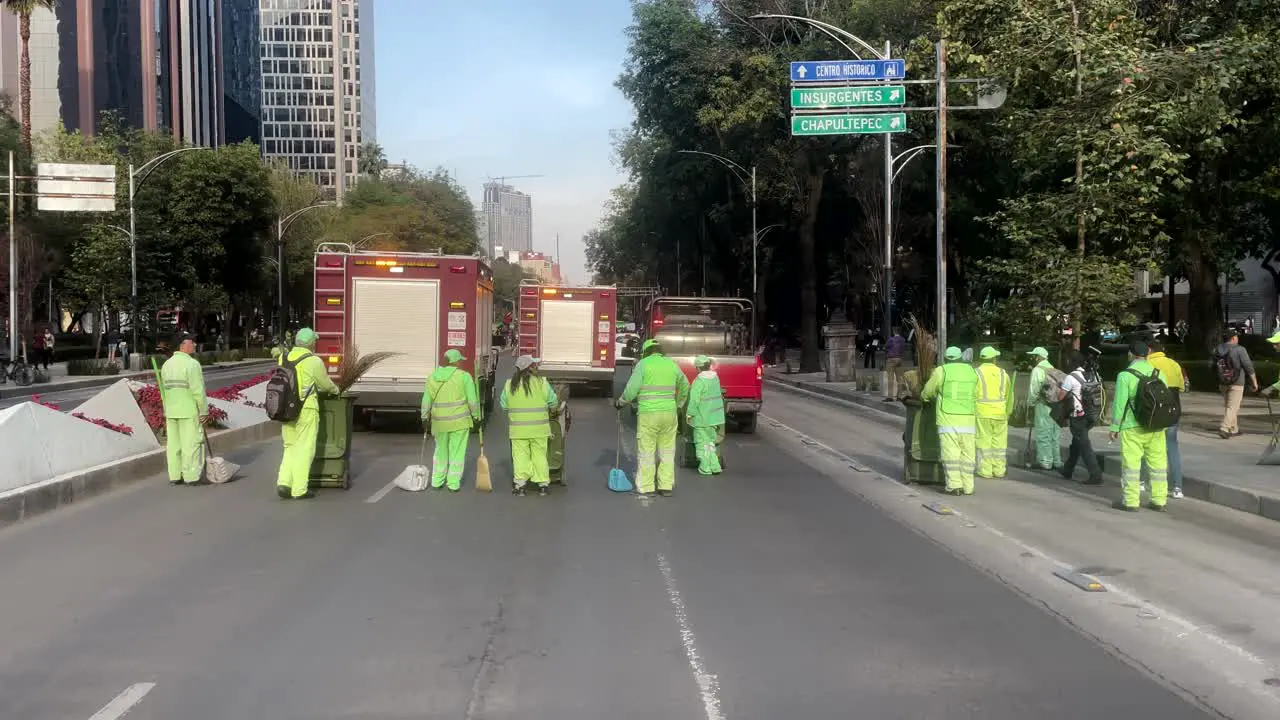 shot of cleaning services from Mexico City sweeping the avenue after the passage of firefighters