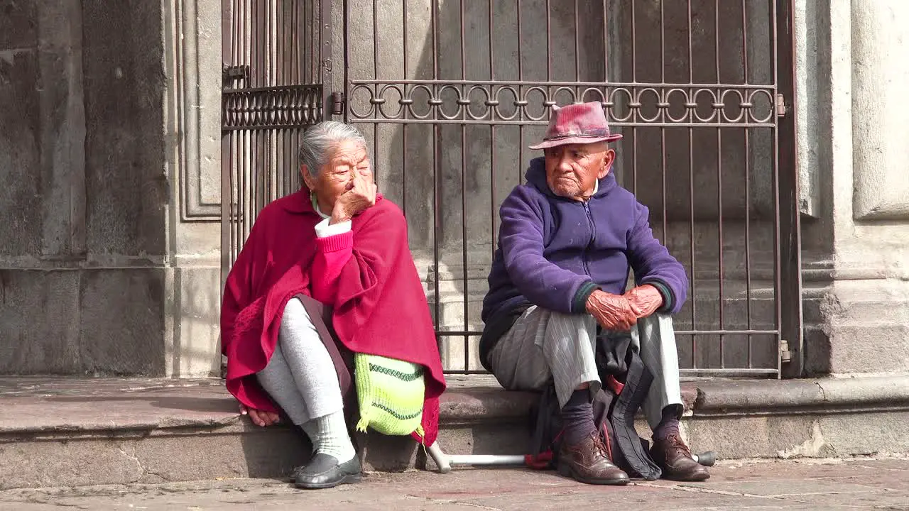 An old couple sits on the street of Quito Ecuador watching people pass by